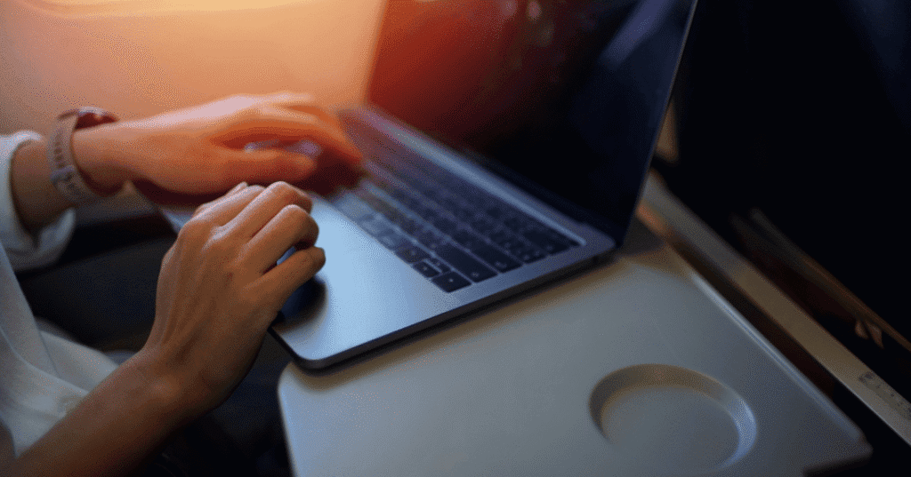Hands using a laptop on airplane