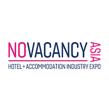 No Vacancy Asia logo featuring the words “NO VACANCY” in bold uppercase letters, with “NO” in pink and “VACANCY” in navy blue. The word “ASIA” appears vertically in pink on the right side. Below, smaller navy text reads “HOTEL + ACCOMMODATION INDUSTRY EXPO” on a light gray background.