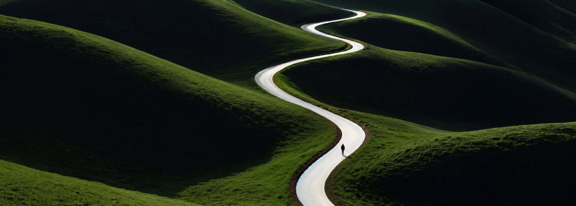 A lone person walks along a bright winding path through rolling green hills under dramatic light and shadow.