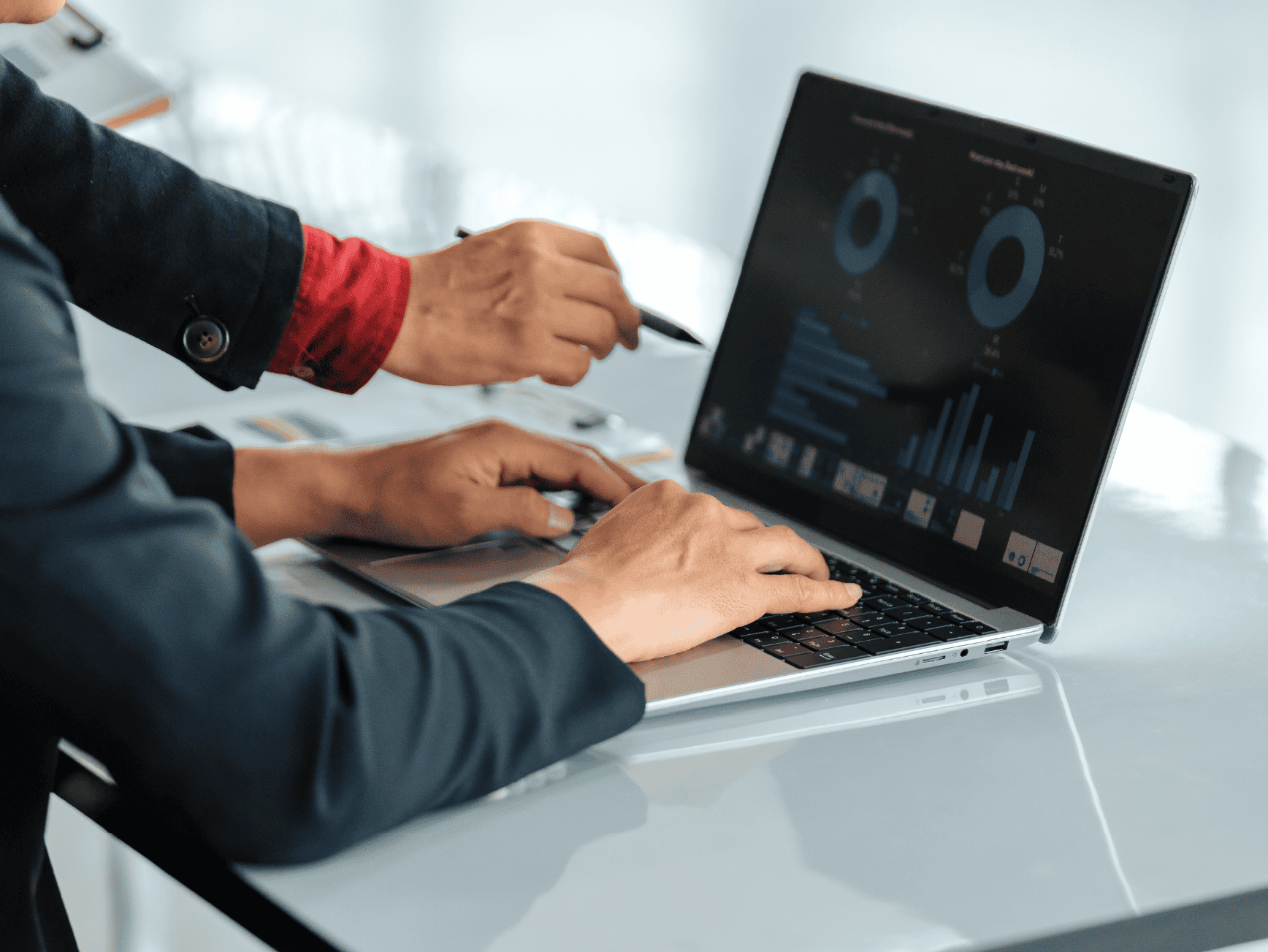 Two business professionals review a laptop displaying a data analytics dashboard with charts during a collaborative office meeting.